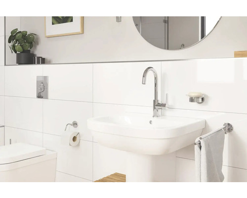 Salle de bains lumineuse avec lavabo, robinet, miroir et carrelage blanc