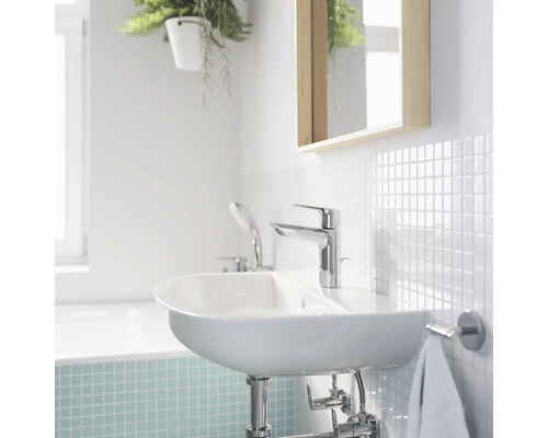 Salle de bain lumineuse avec lavabo, robinet, miroir et carrelage