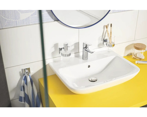 Salle de bain lumineuse avec lavabo, robinet, distributeur de savon, gobelet à brosse à dents et porte-serviettes