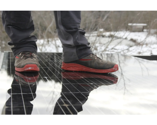 Un homme avec des chaussures de travail se tient sur une installation solaire.