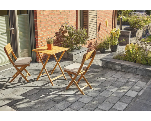 Scène de jardin avec table en bois et deux chaises sur pavés devant une maison