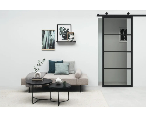 Salon avec porte coulissante, canapé, tables basses et décorations murales pour un intérieur moderne.