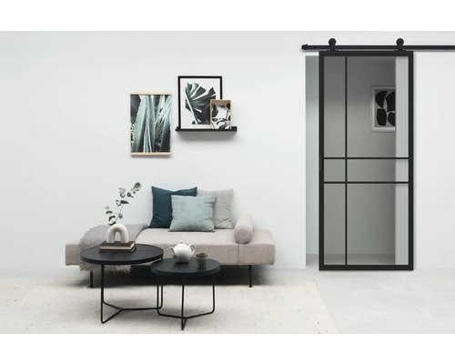 Salon avec porte coulissante, canapé, tables basses et décorations murales