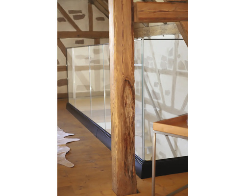 Innenansicht eines Hauses mit einem Treppengeländer aus Glas und einem Holzpfosten