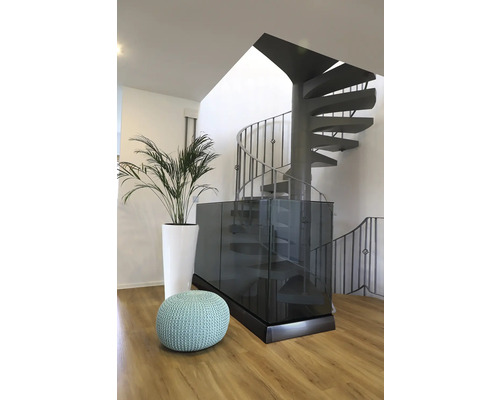 Innenaufnahme eines Raumes mit Wendeltreppe, Sitzhocker und Pflanze