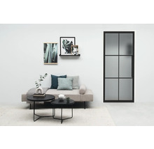 Salon lumineux avec canapé, tables basses, images de plantes et une porte avec insert en verre.