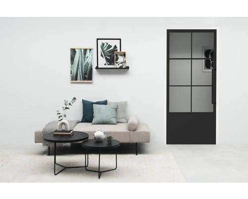 Wohnzimmer mit Sofa, Couchtischen und einer Tür mit Glaseinsatz