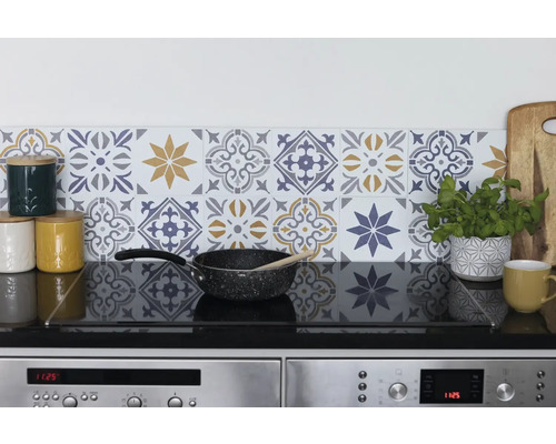Scène de cuisine avec mur carrelé au design floral, plaque de cuisson et ustensiles de cuisine.