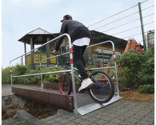 Fahrradfahrer fährt mit einem BMX-Rad über eine temporäre Brücke.