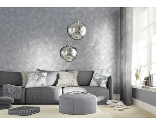 Salon avec canapé, coussins, tabouret et décoration murale.