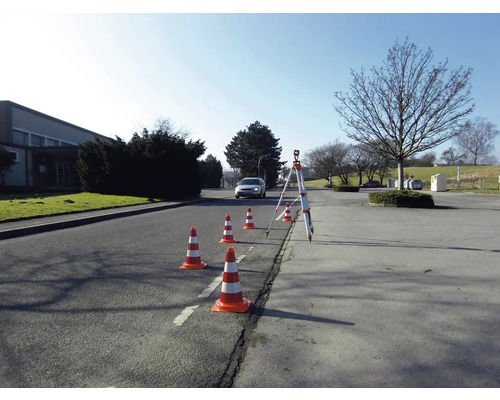Scène extérieure avec des cônes de signalisation et un niveau monté sur un trépied pour les mesures.