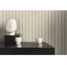 Gros plan d''un mur avec du papier peint à panneaux de bois, une sculpture, une plante et une tasse sur une table.