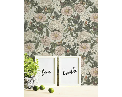 Scène d''intérieur avec papier peint fleuri, deux photos encadrées avec les mots amour et respiration, plante en pot et citrons verts