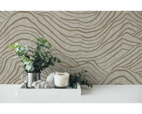 Papier peint décoratif avec motif ondulé servant de toile de fond à un arrangement avec bougie et plantes.
