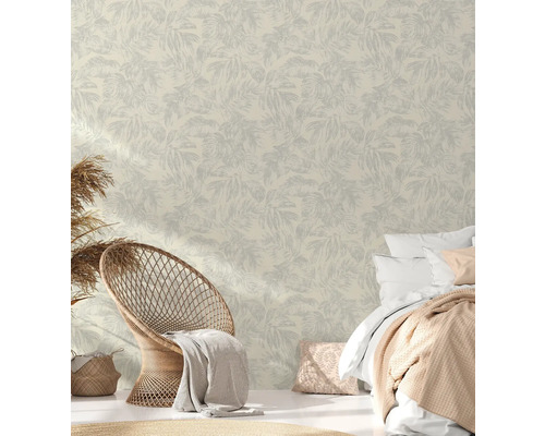 Chambre claire avec papier peint à feuilles, fauteuil en rotin et lit