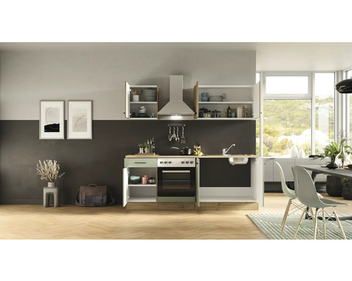 Cuisine avec évier, cuisinière, hotte et armoires suspendues dans une pièce lumineuse.