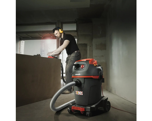 Artisan avec aspirateur lors de travaux de rénovation dans une pièce.