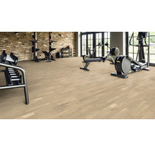 Salle de sport avec plancher en bois, haltères et appareils d'entraînement.