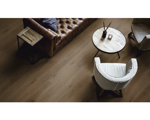 Salon avec canapé en cuir marron, tables en bois et parquet en bois.