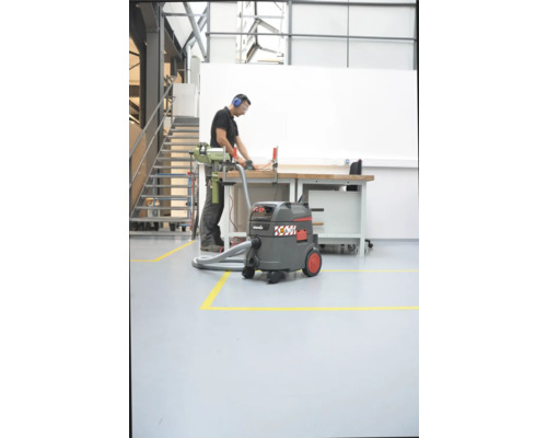 Situation d''atelier avec aspirateur eau et poussière, établi et ouvrier avec protection auditive et lunettes de protection