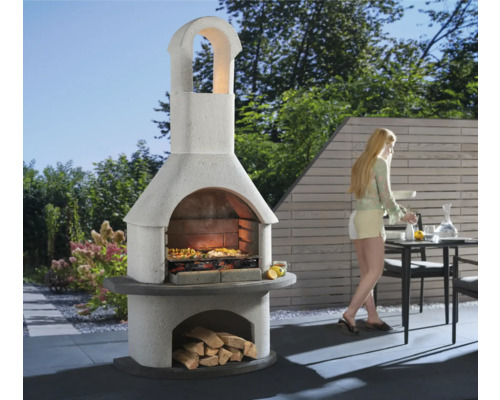 Barbecue de jardin en maçonnerie avec des bûches et une femme dans le jardin