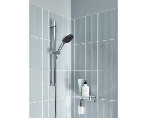 Barre de douche avec douchette, étagère et produits cosmétiques dans une salle de bains carrelée en bleu.