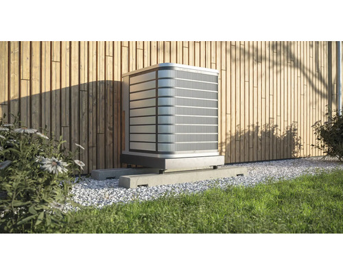 Climatiseur extérieur sur socle en béton devant un mur en bois