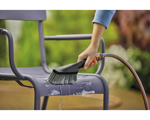 Reinigung einer Gartenstuhl-Oberfläche mit einer Bürste und einem Wasserschlauch