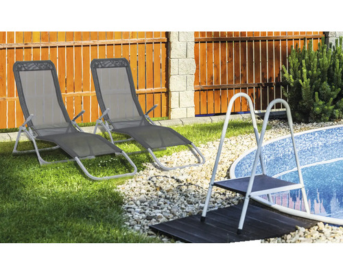 Deux chaises longues à côté d''une piscine avec une échelle