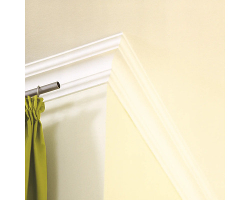 Gros plan d''une moulure décorative blanche sur un mur avec une tringle à rideaux et un rideau.