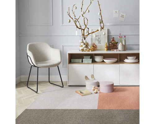 Dekoratives Wohnzimmer mit Sessel, Teppich und Osterschmuck auf einem Sideboard
