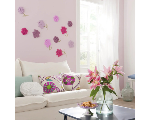 Wohnzimmer mit weissem Sofa, Zierkissen und Wanddekoration mit Blumenmotiven