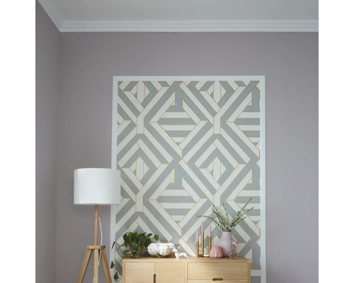 Pièce décorative avec papier peint à motifs géométriques, lampadaire et commode en bois