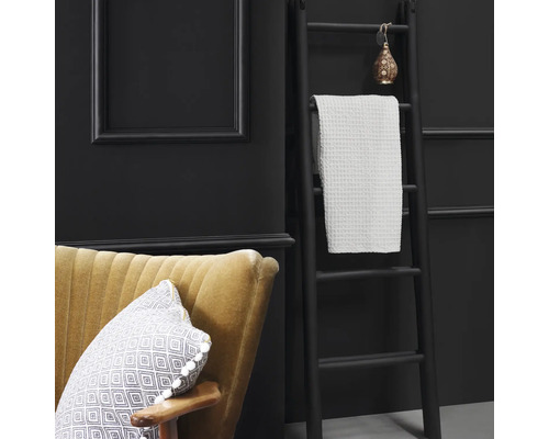 Dekorative Szene mit Leiter, Handtuch, Sessel und Kissen vor dunklem Hintergrund.