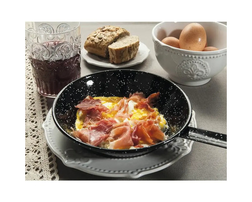 Poêle avec œufs au plat et jambon sur une table dressée avec pain, œufs et boisson