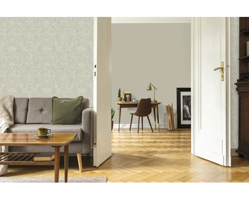 Salon lumineux avec papier peint à motifs floraux, canapé et parquet