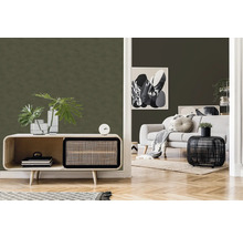 Salon avec murs verts texturés, canapé clair et mobilier en bois pour une ambiance claire et organisée