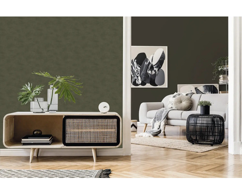 Salon avec murs verts texturés, canapé clair et mobilier en bois pour une ambiance claire et organisée