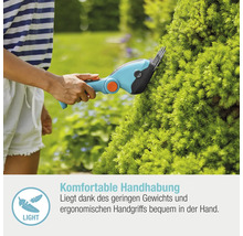 Frau schneidet mit einer Akku-Grasschere eine Hecke