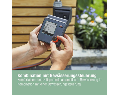 Une personne utilise un programmateur d''arrosage Gardena dans le jardin.