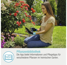 Frau benutzt Tablet im Garten mit Pflanzenbibliothek App
