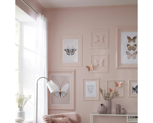 Salon avec cadres et motifs de papillons au mur, lampadaire et vases décoratifs sur la table.