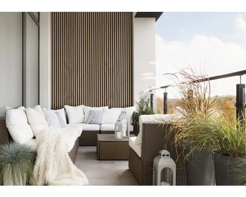 Balcon avec coin salon en rotin, coussins, couverture, lanternes et pots à plantes.