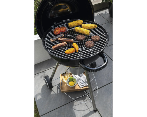Kugelgrill mit Grillgut wie Maiskolben, Wurst und Burger auf dem Grillrost