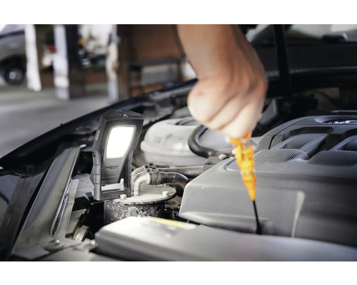 Un ouvrier vérifie le niveau d''huile avec une lampe torche sur le moteur d''une voiture