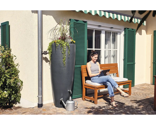 Regentonne mit Bepflanzung und Frau mit Tablet auf einer Bank