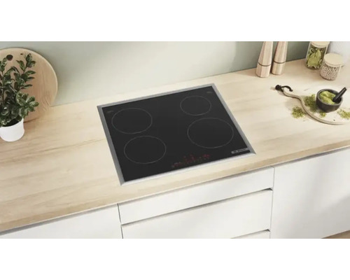 Plaque de cuisson vitrocéramique noire avec quatre zones de cuisson dans une cuisine claire