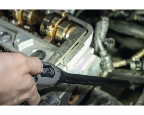 Une main tenant une lampe d''inspection dans le compartiment moteur.