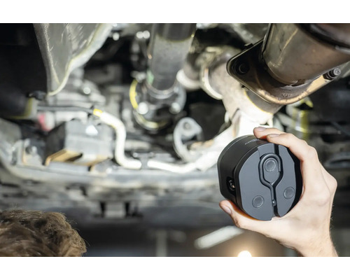 Une personne tient une lampe d''inspection sous une voiture.