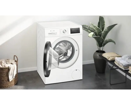 Machine à laver blanche avec porte ouverte dans une pièce lumineuse